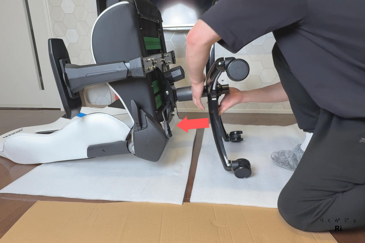AKRacingゲーミングチェアの組み立て工程。キャスターを取り付けた5本足ベースをガスシリンダーに差し込む様子。