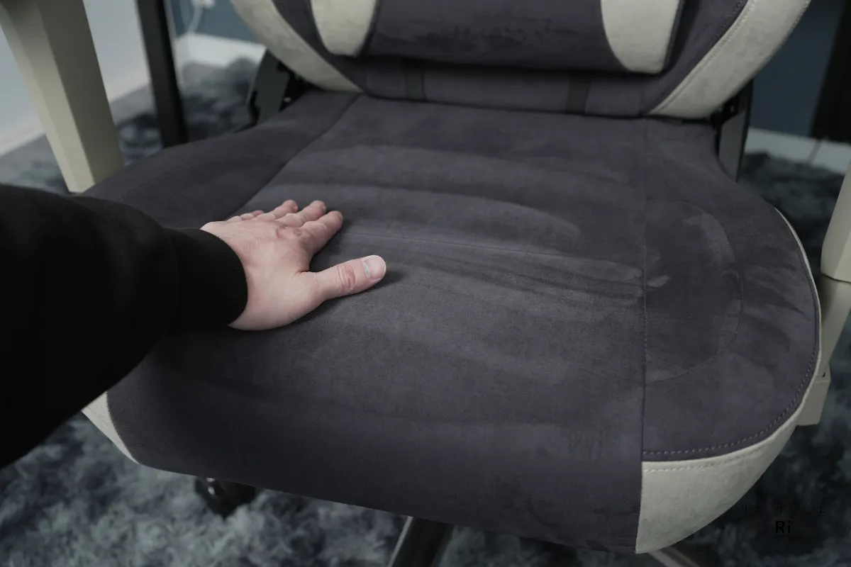張地のスエード調ファブリックを手で触れている座面アップ