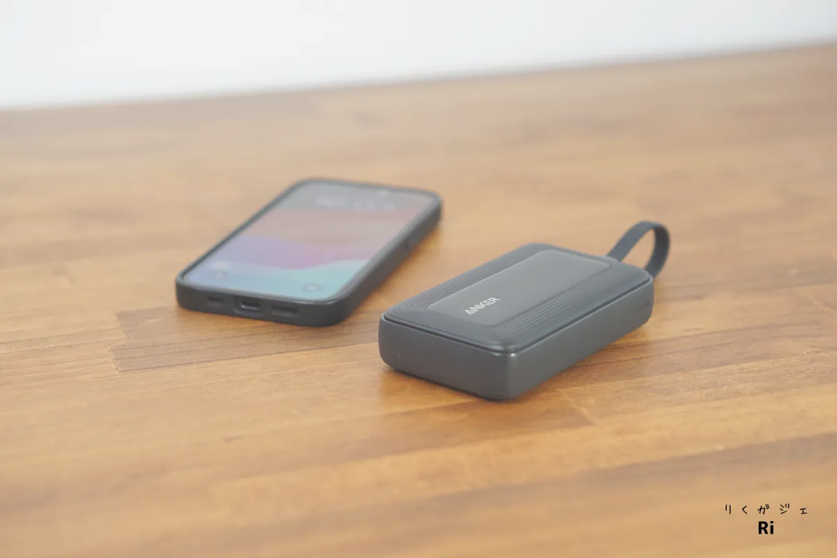 Anker Zolo Power Bank（10000mAh, 30W）をスマートフォンの隣に置いた使用イメージ。外観は波紋状の立体ライン加工が施され、シンプルながらもアクセントの効いたデザイン。
