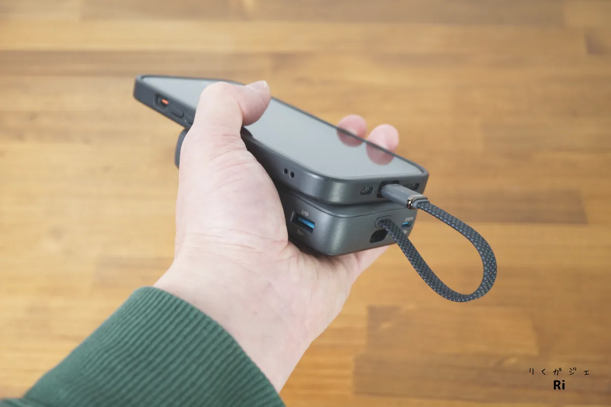 Anker Zolo Power Bank（10000mAh, 30W）をスマートフォンと重ねて手に持った状態の使用イメージ。内蔵USB-Cケーブルが余らずスッキリ収まり、携帯性と操作性が高い。