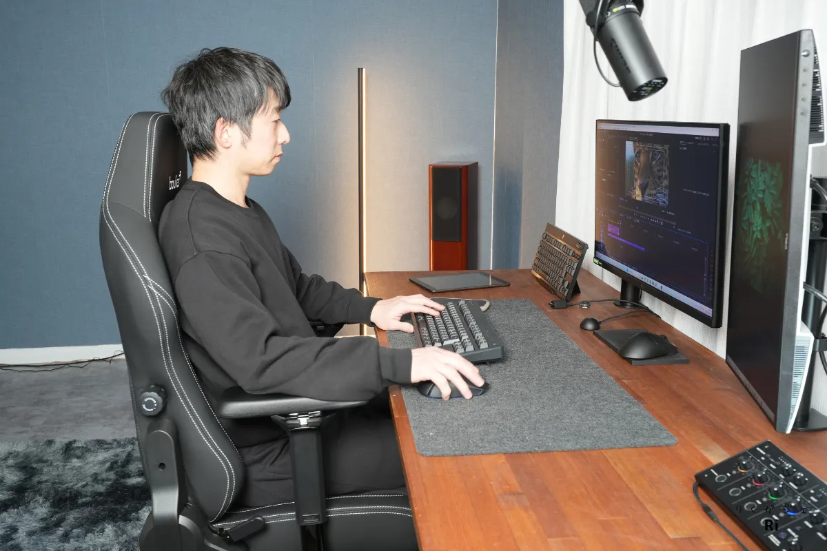 デスク前でBoulies Master Rexに座り、キーボード操作をしている男性。直立姿勢でも快適に座れるチェアの使用シーン