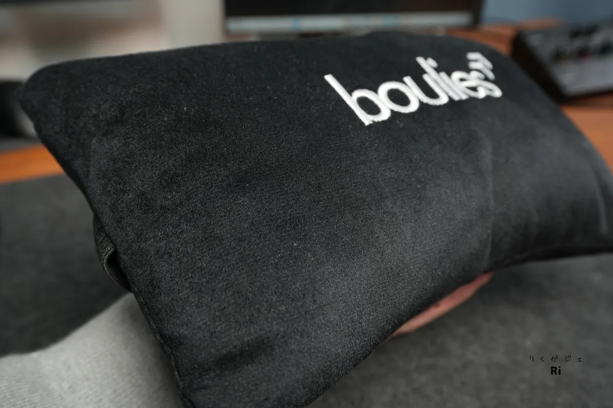 Boulies ロゴ入りの黒いヘッドレストクッションを手に持っている様子