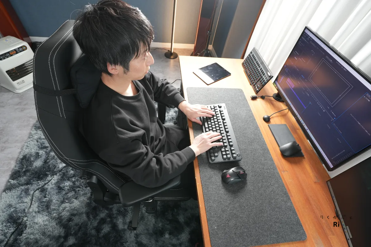 ゲーミングチェアに座り、肘を90度に保ってタイピングする男性のデスクワークの様子