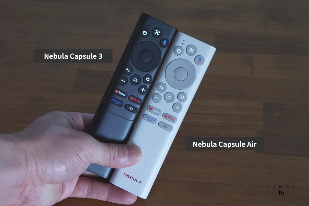 Nebula Capsule 3とCapsule Airのリモコンを手に持って比較している様子。どちらのリモコンも振動センサー搭載で、暗所でも操作しやすいバックライト付きボタンを搭載。