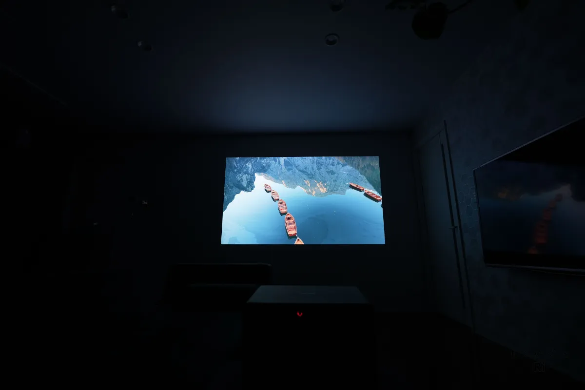 部屋を暗くした状態でプロジェクター映像を投影し、鮮やかな映像がくっきりと映し出されている様子を撮影した写真
