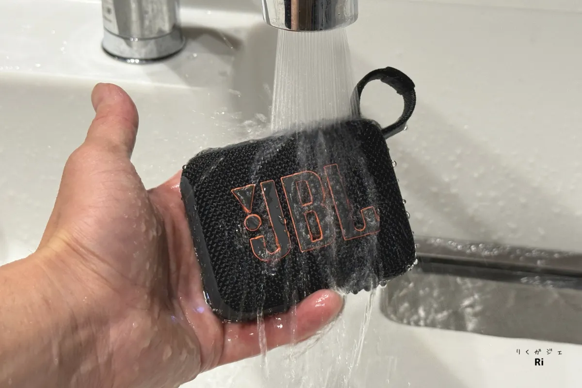 JBL Go 4の防水性能を示す写真。蛇口の水を直接かけても使用できるIP67対応ポータブルスピーカー