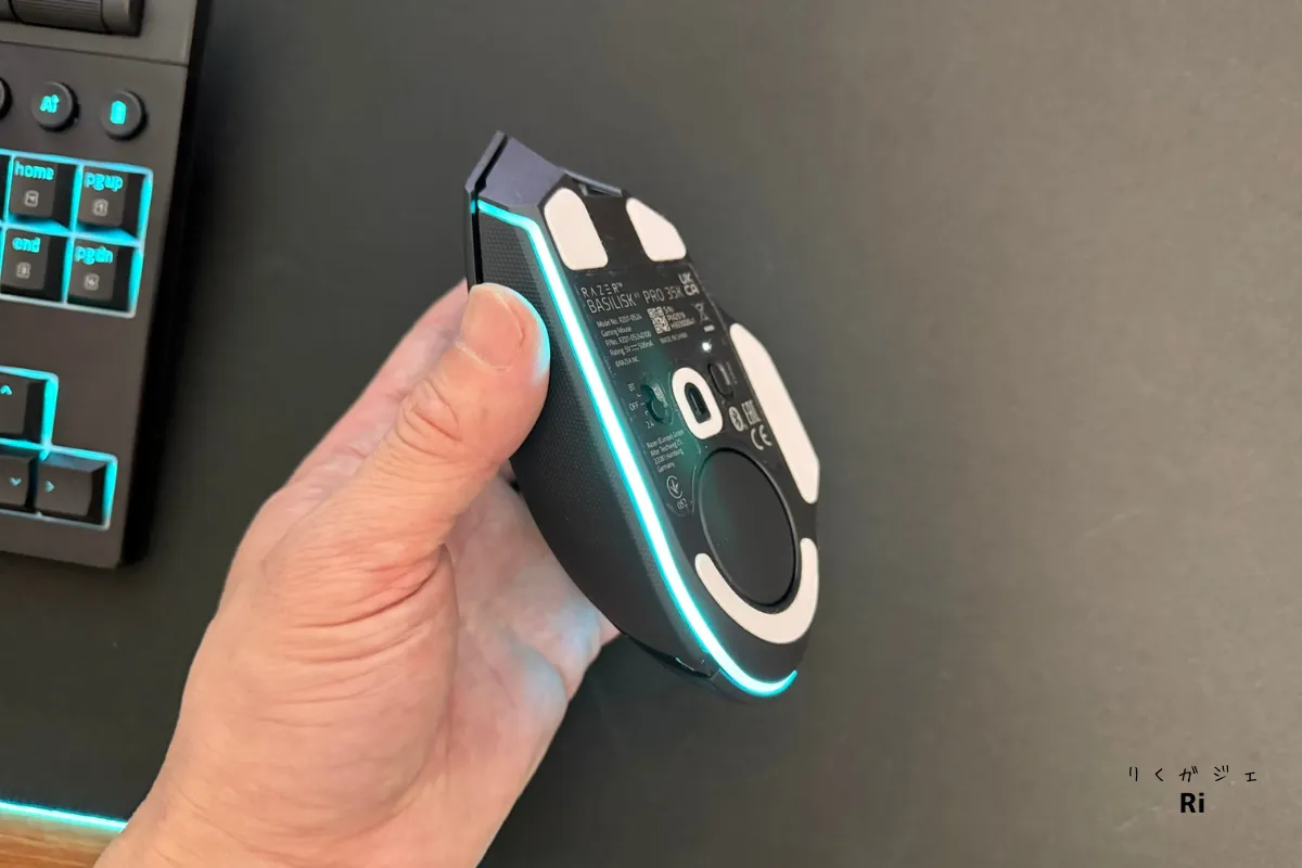 Razer Basilisk V3 Pro 35Kを手に取り、底面のセンサーとPTFEマウスソールを確認している様子