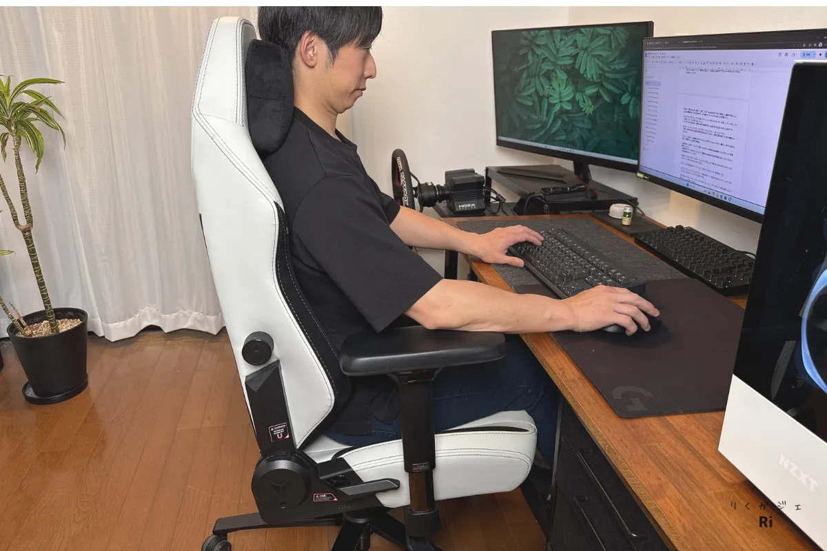 Secretlab TITAN Evoのホワイトモデルに座り、マグネット式のヘッドレストを使用しながらデュアルモニターで作業する男性。背筋を伸ばした姿勢を保ちつつ、快適にタイピングを行っている様子。