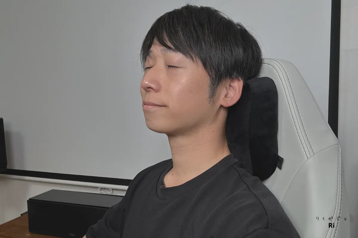 Secretlab TITAN Evoのチェアに座り、黒いランバーピローにもたれて目を閉じてリラックスしている男性。ヘッドレストのフィット感や快適性を確認している様子。