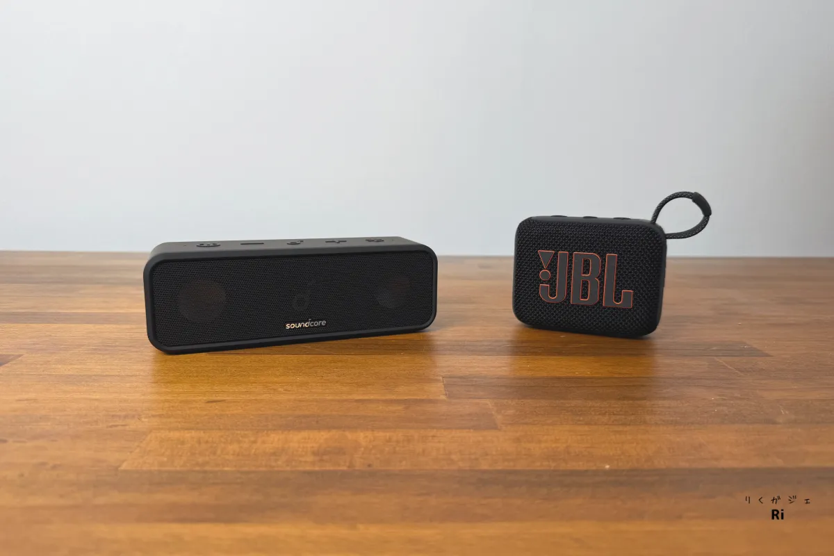 Anker Soundcore 3とJBL GO 3を並べた比較写真。木目のテーブル上に設置されており、サイズとデザインの違いがわかる。