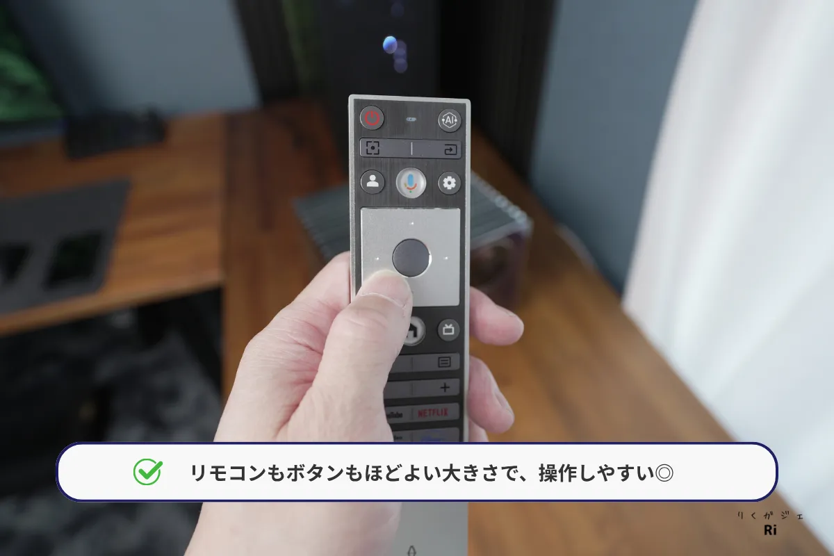 付属リモコンを手に持ち、ボタンの配置や大きさを確認している様子。
