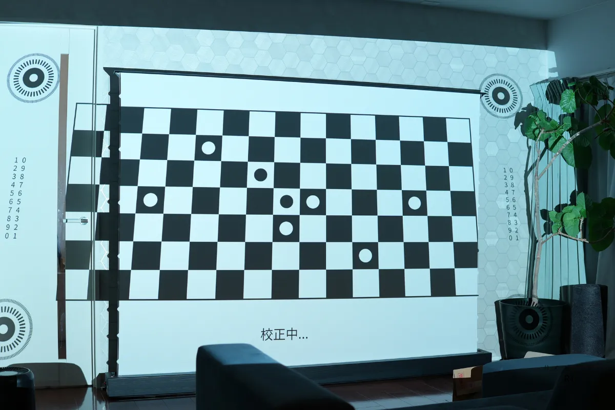 自動スクリーンフィット機能を検証。スクリーンに投影されたチェッカーパターンを使い、映像の位置やサイズを自動調整している様子。